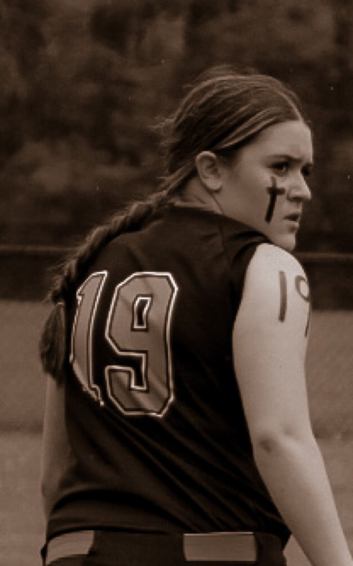 Sepia portrait of a softball player in her number 19 jersey looking over her shoulder