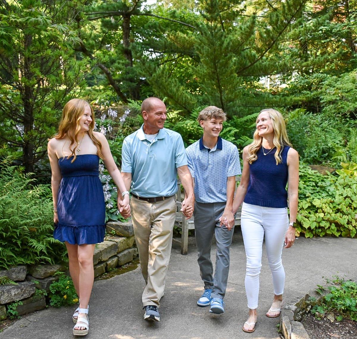 Family of four walking together on a wooded path during a family session in Central Ohio