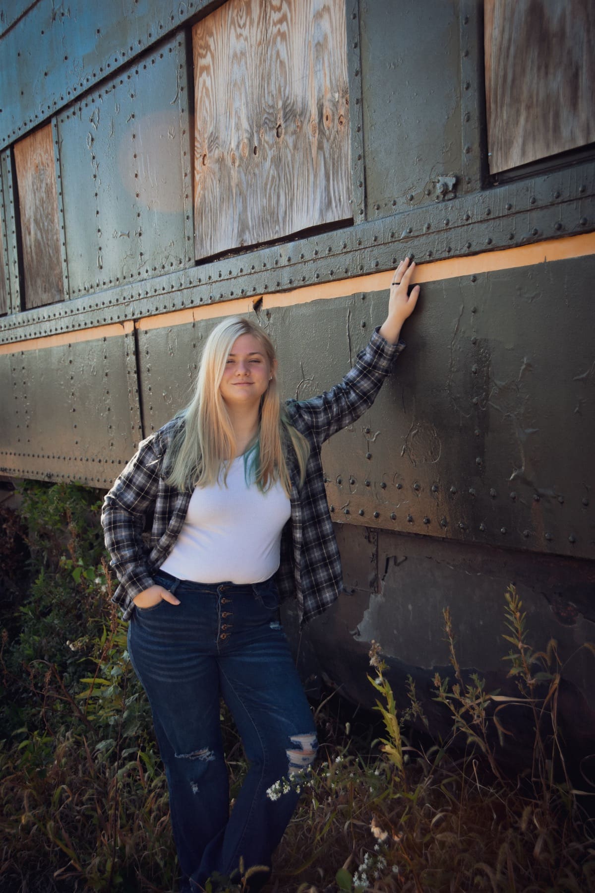 Senior girl in a flannel leaning against a vintage rail car
