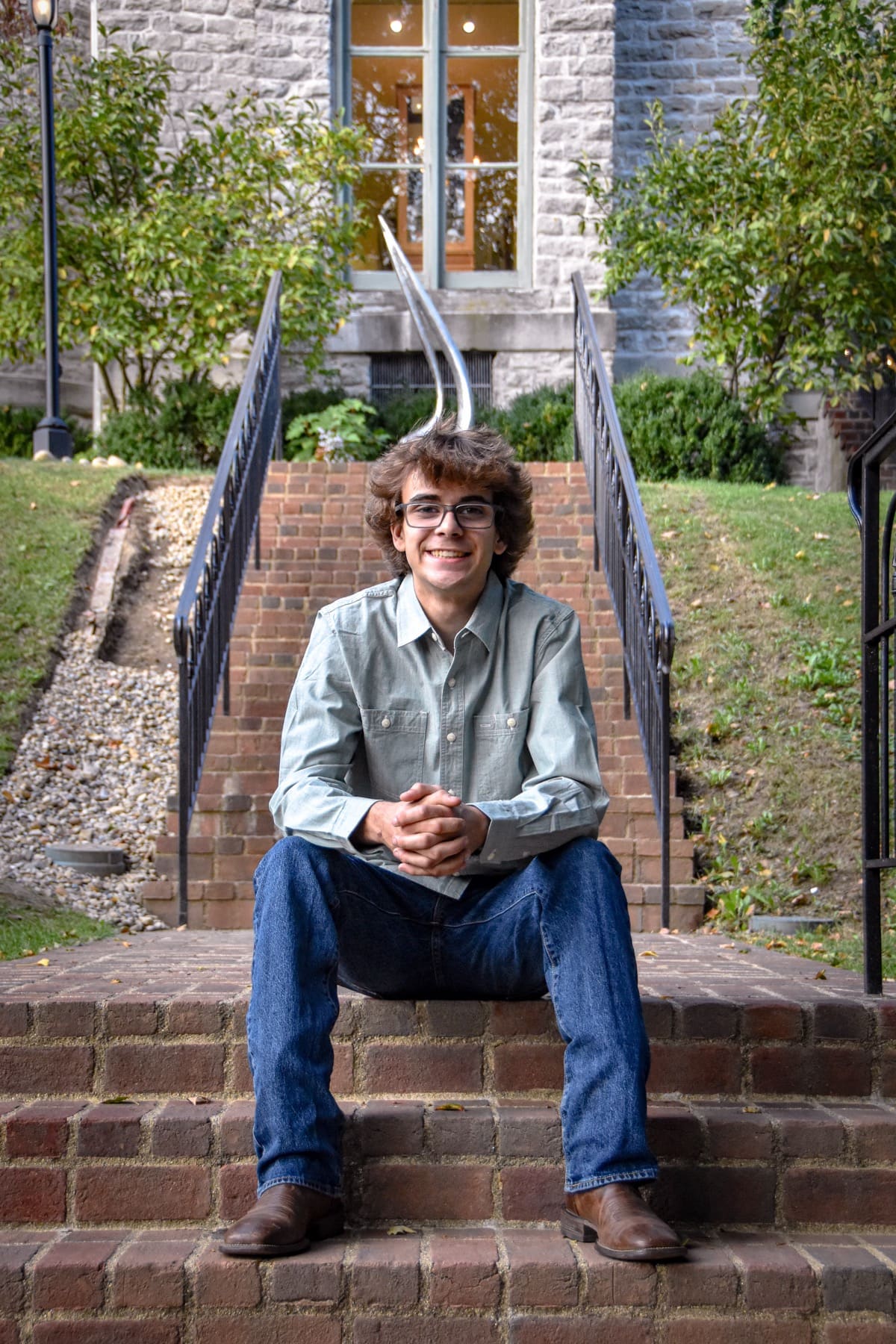 Smiling senior in glasses sitting on brick campus steps in Delaware, Ohio