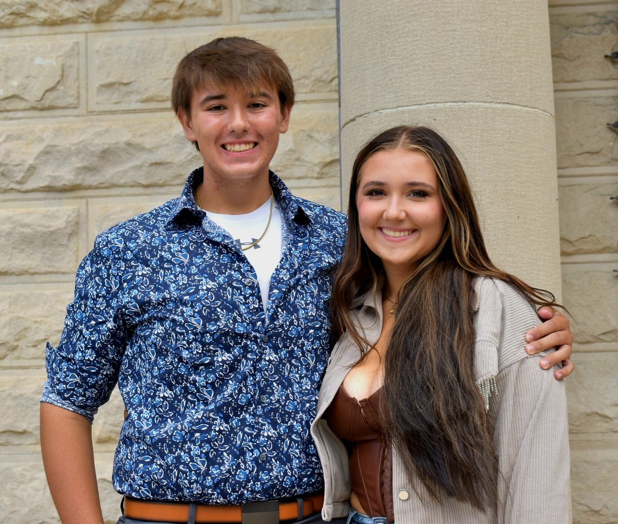Brother and sister posed together against a stone wall