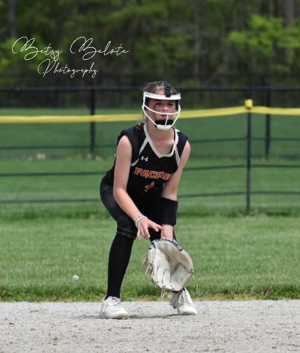 Young softball player in defensive ready stance with glove low anticipating ground ball