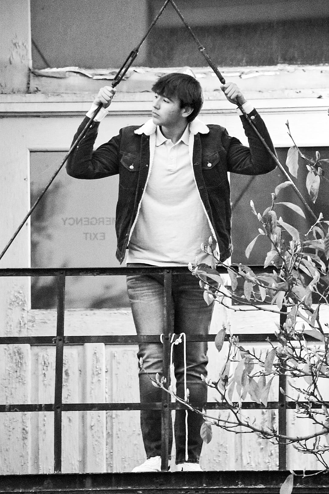 Black and white artistic portrait of young man on fire escape platform, dramatic and introspective mood