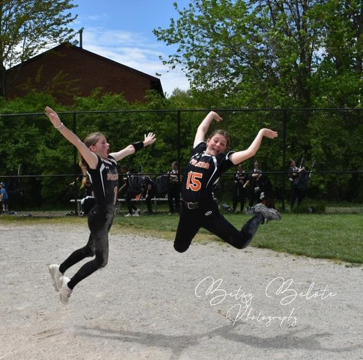 Two Pacers softball teammates leaping into the air in celebratory jump after victory